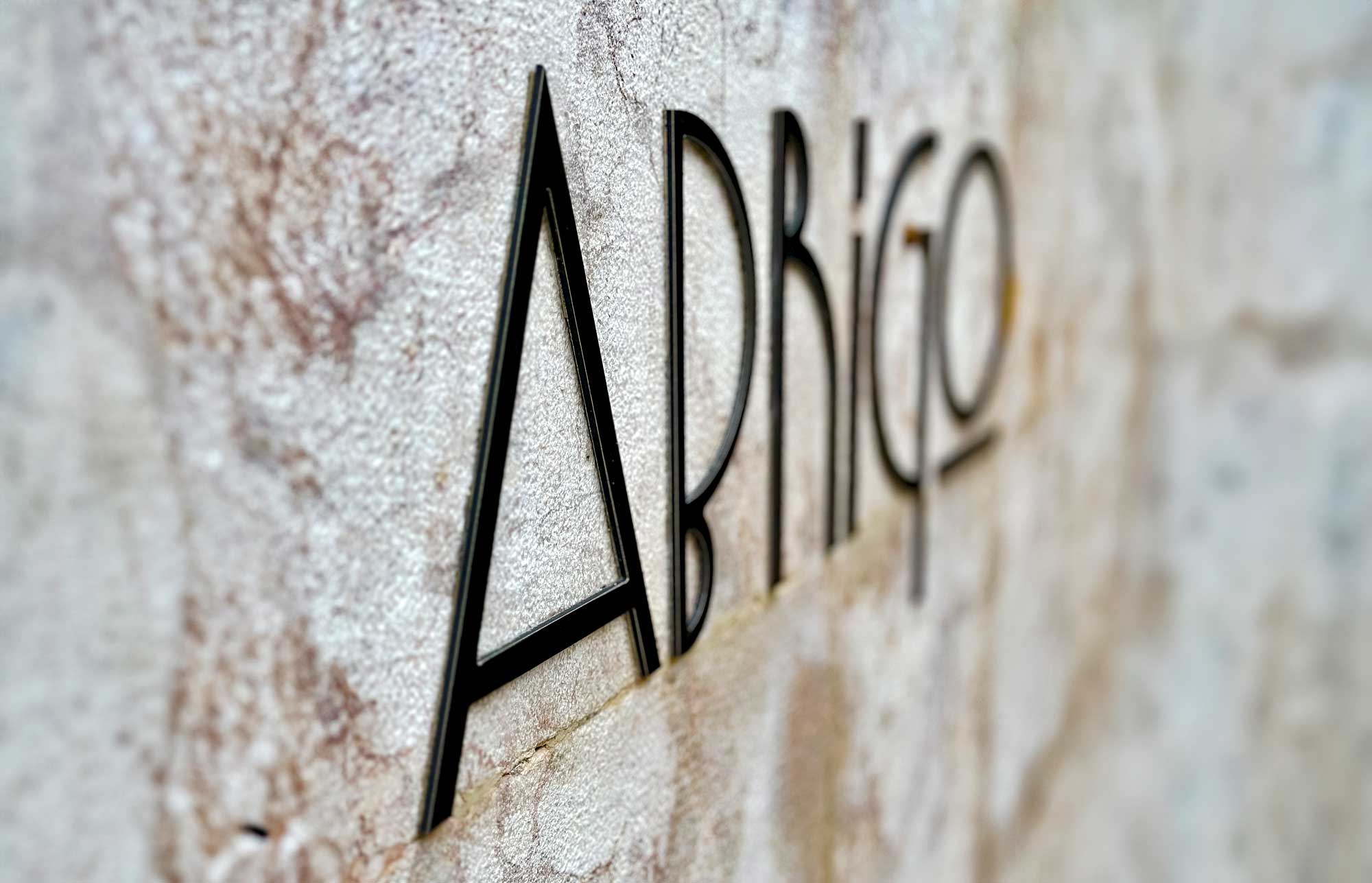 Abrigado means sheltered or protected in Portuguese