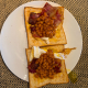 the runny eggs and baked beans topped with crispy bacon on toast breakfast sandwich